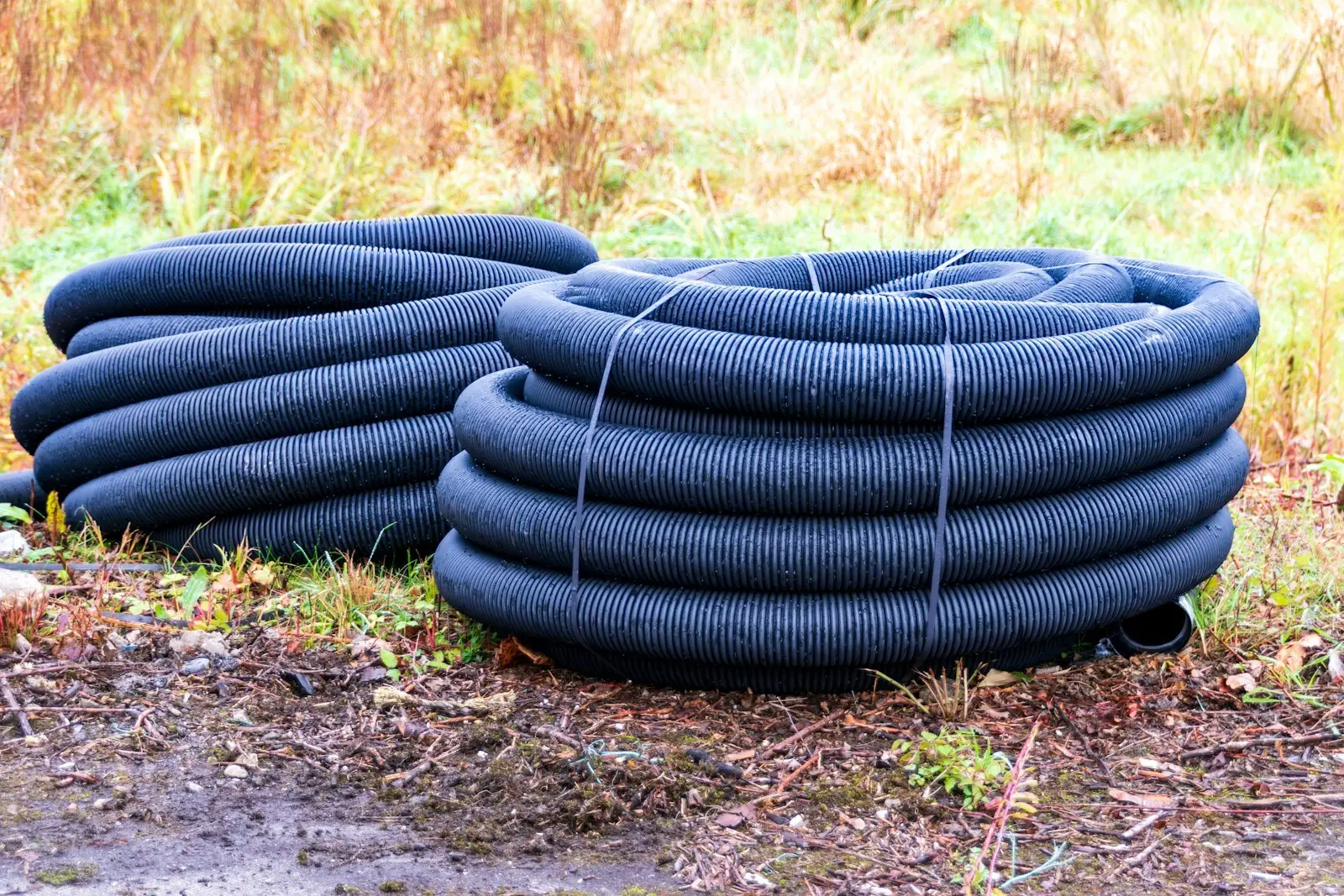 Coils of black perforated corrugated drainage pipe used for French drain installation