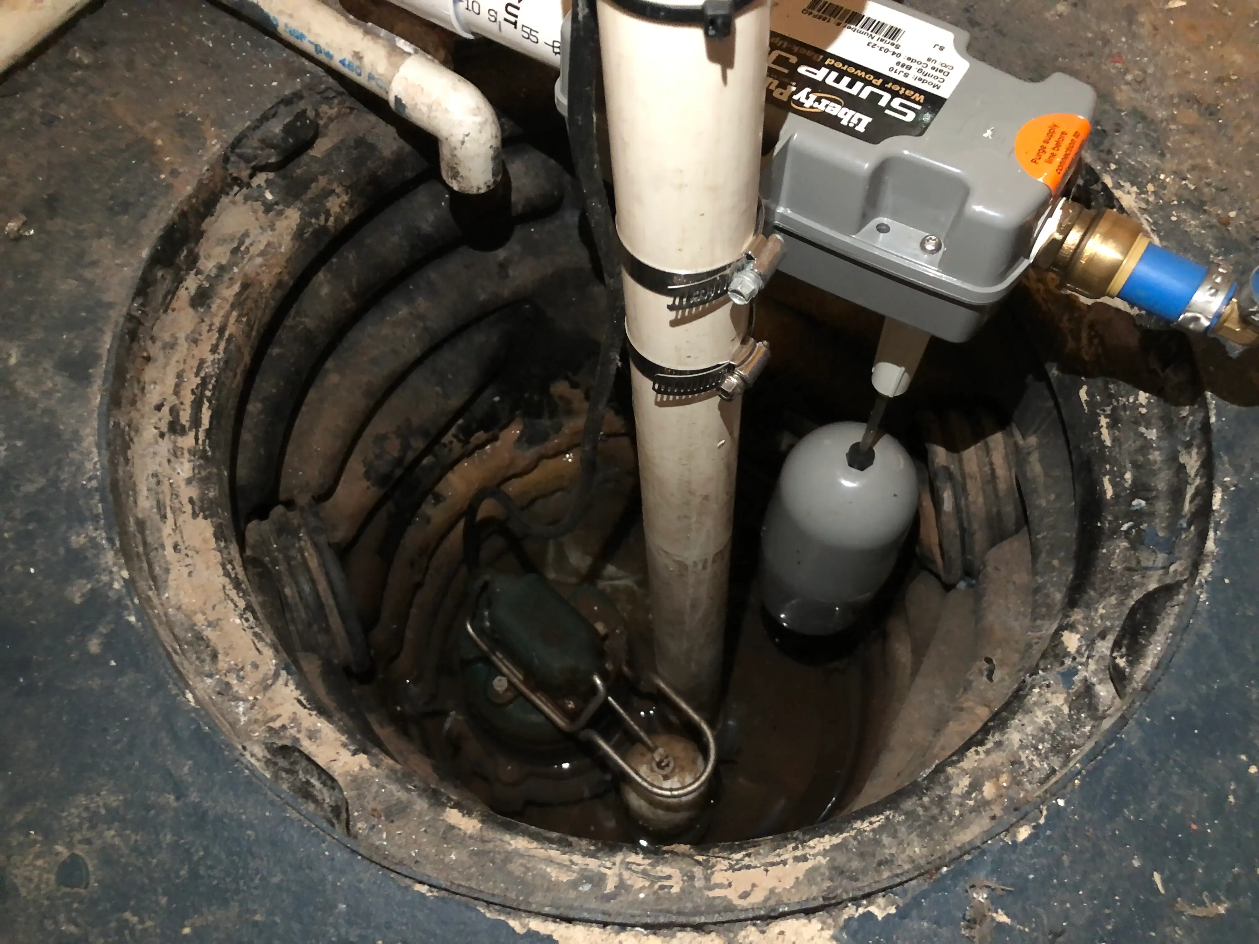 Submersible sump pump installed in a basement sump pit with discharge piping