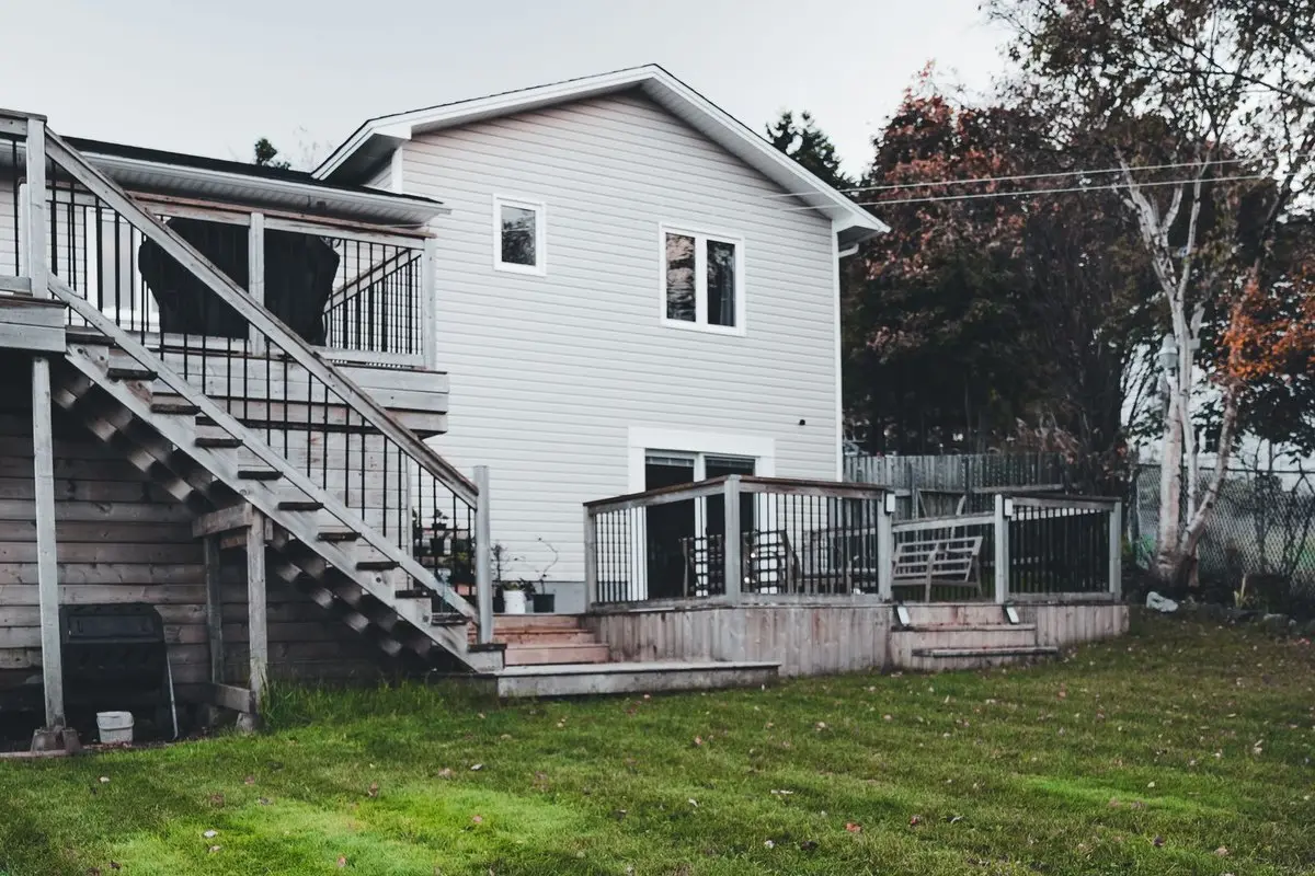 Healthy, well-drained green residential backyard lawn behind a home with a wooden deck
